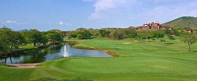 lush golf course with fountain pond and resort buildings in background