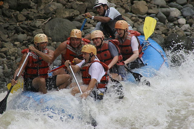 group of rafters paddling through whitewater rapids wearing helmets