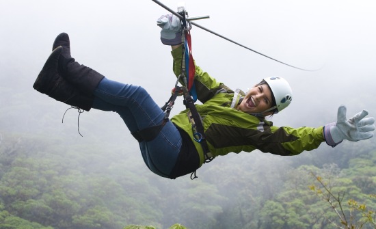 Woman smiling while riding zipline above cloud forest.