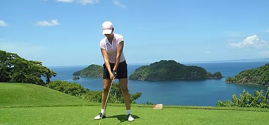 woman golfer preparing swing with scenic ocean islands in background