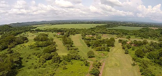 aerial view of expansive green golf course surrounded by farmland