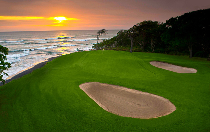 golf course green with sand bunkers overlooking ocean sunset view