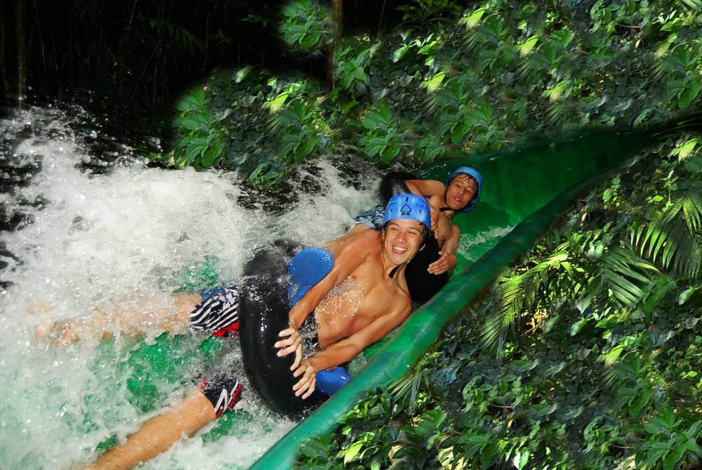 smiling friends tubing down water slide surrounded by lush greenery